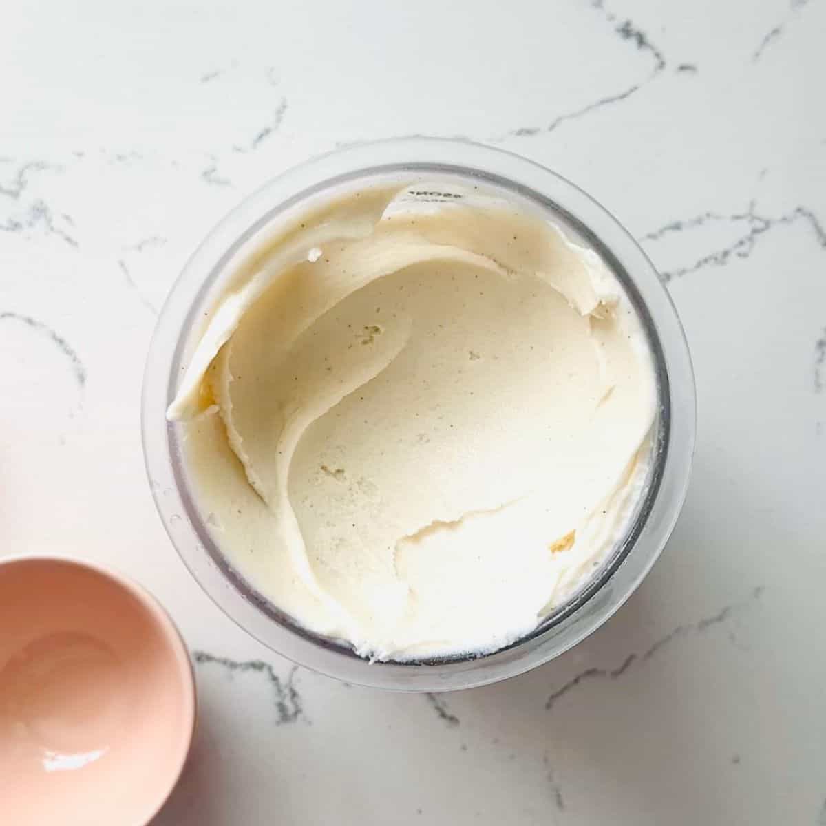 Creamy high-protein vanilla ice cream in a ninja creami pint ready to be scooped.