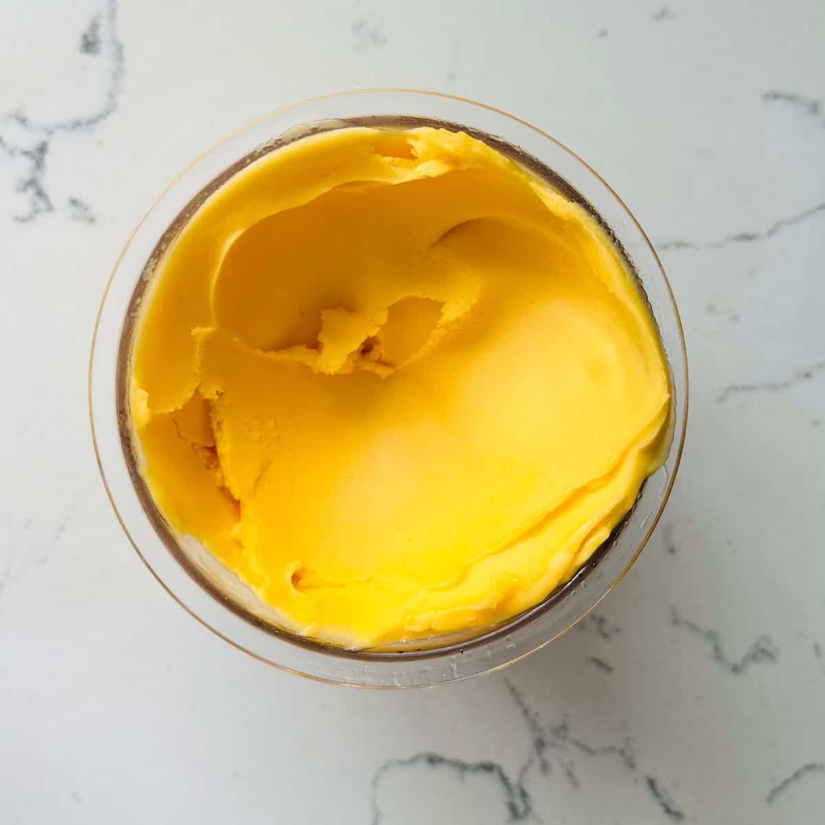 Peach and mango sorbet looking very creamy in a ninja creami container.