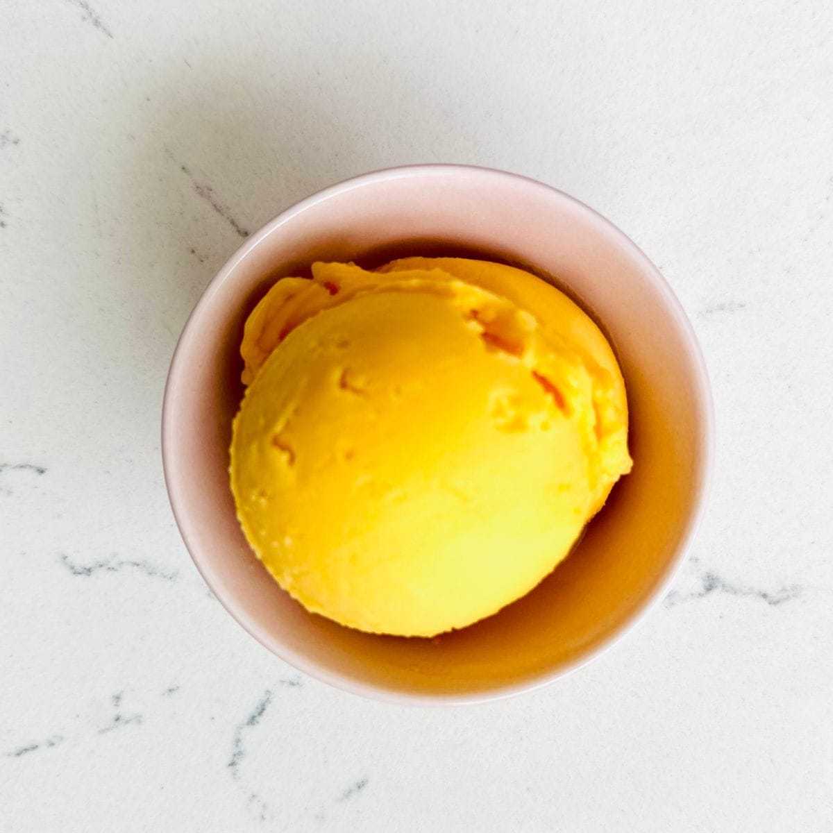 Scoops of Peach and mango sorbet in a bowl ready to be enjoyed.