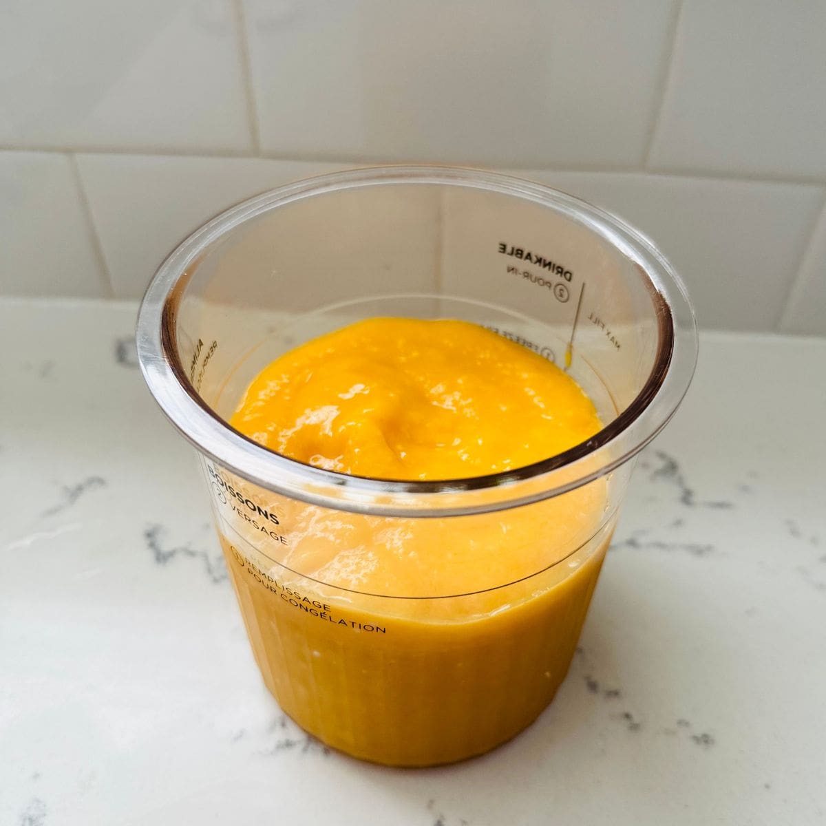 Peach and mango sorbet mixture in a ninja creami container before freezing.