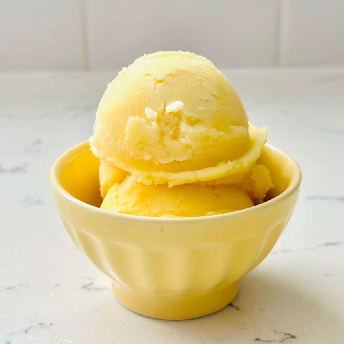 Scoops of dole whip ice cream on a yellow bowl ready to be enjoyed.