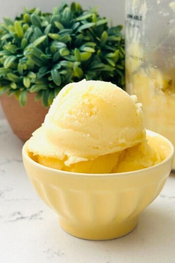 Scoops of dole whip ice cream on a yellow bowl ready to be enjoyed.