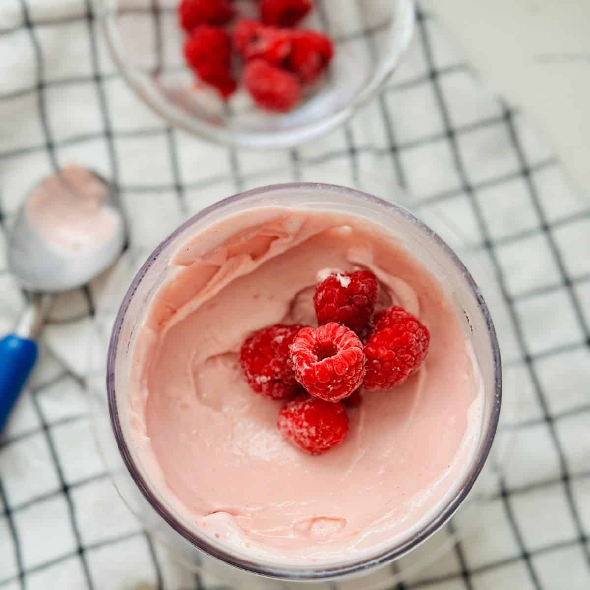 Rose raspberry ice cream freshly spun and topped with whole raspberries.