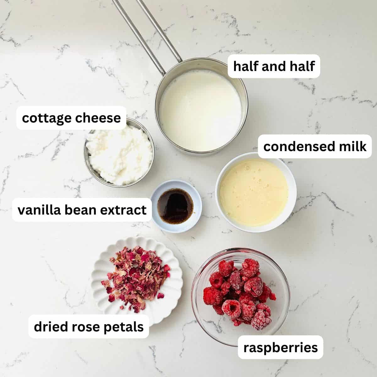 Ingredients for rose raspberry ice cream arranged neatly on a marble table.