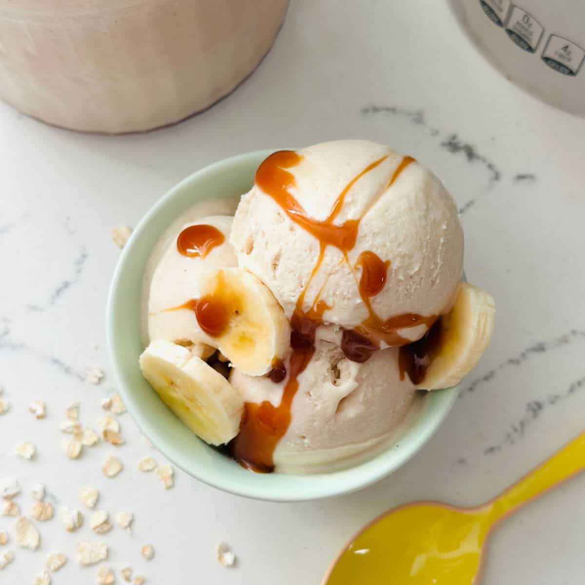 Scoops of Ninja Creami Overnight Oats Ice Cream topped with oats and fruit in a bowl.