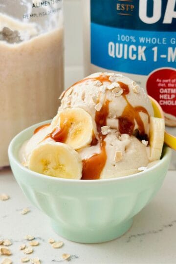 Scoops of Ninja Creami Overnight Oats Ice Cream topped with oats and fruit in a bowl.