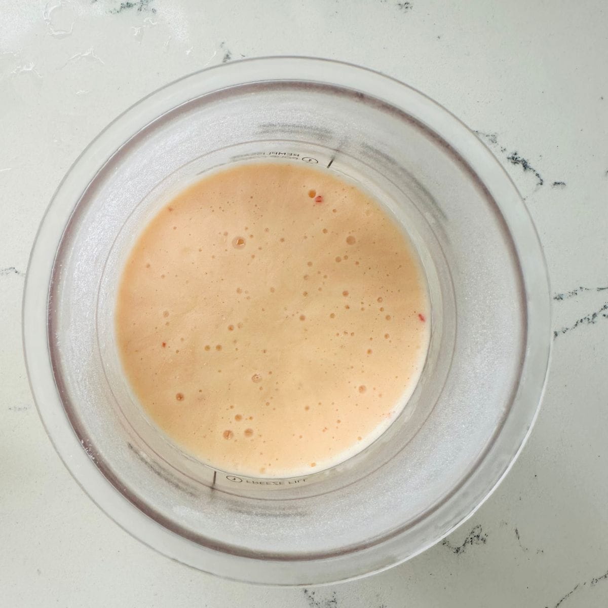 Red pepper jelly ice cream mixture poured into Ninja Creami pint container and frozen flat for 24 hours.