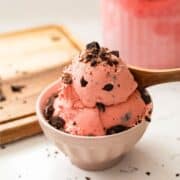 Homemade Black Forest ice cream with maraschino cherries base and chocolate chunks, served in a small bowl.