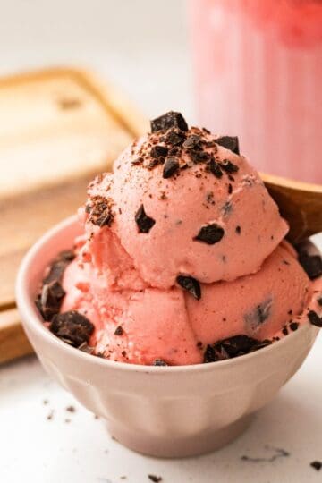 Homemade Black Forest ice cream with maraschino cherries base and chocolate chunks, served in a small bowl.