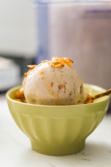 Bowl of Ninja Creami maple cinnamon crunch ice cream with maple drizzle and cinnamon crunch on top.