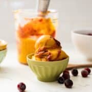 Bowl of creamy mango cranberry ice cream with visible cranberry streaks.
