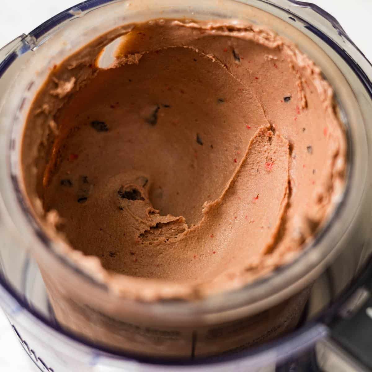 Chocolate strawberry ice cream swirled together in a dish with a spoon ready to scoop.