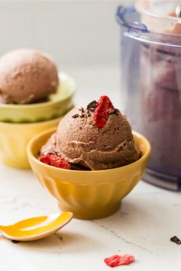 Scoop of chocolate strawberry ice cream made in the Ninja Creami in a bowl with fresh strawberries.