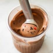 Chocolate strawberry ice cream swirled together in a dish with a spoon ready to scoop.