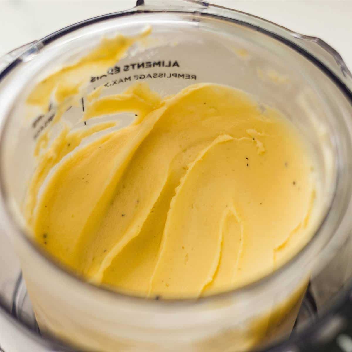 Ninja Creami mango cardamom ice cream in a pint container with a creamy swirl on top.