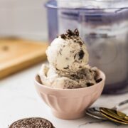 Scoops of high protein cookies and cream ice cream served in a small pink bowl with cookie crumbs on top.