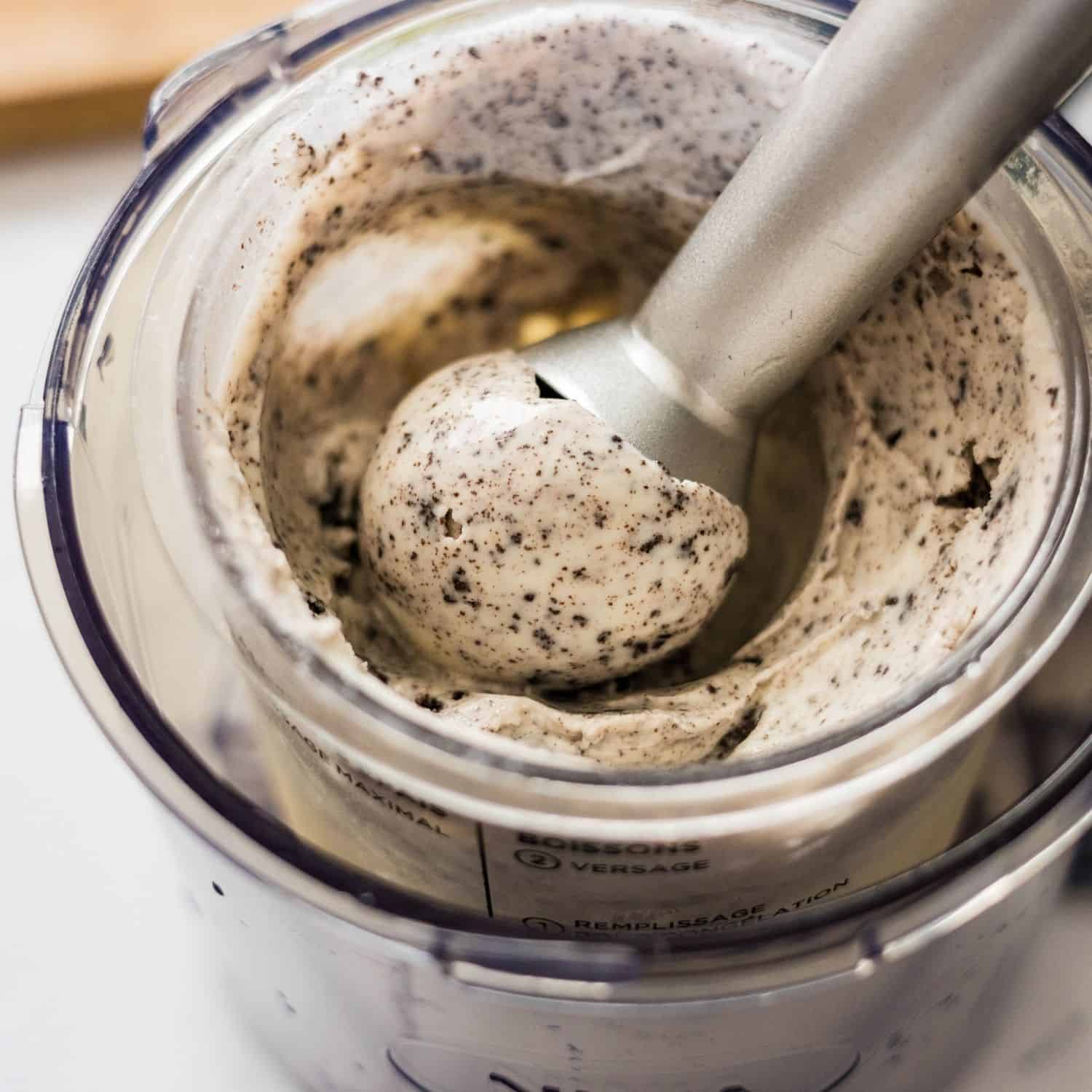 A scoop of creamy high protein cookies and cream ice cream lifted from a Ninja Creami pint, showing a smooth texture with cookie specks.