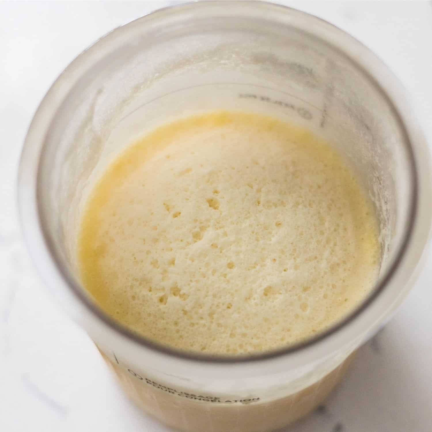 Frozen high protein cookies and cream ice cream base in a Ninja Creami pint before spinning.