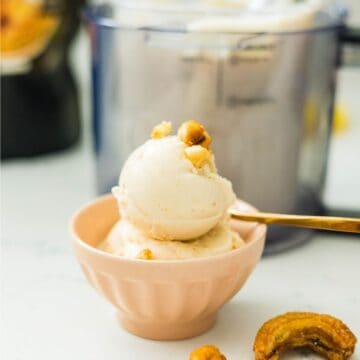 Banana ice cream served in a bowl with crunchy banana chips beside the Ninja Creami machine.