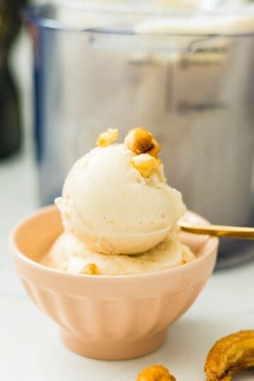 Banana ice cream served in a bowl with crunchy banana chips beside the Ninja Creami machine.