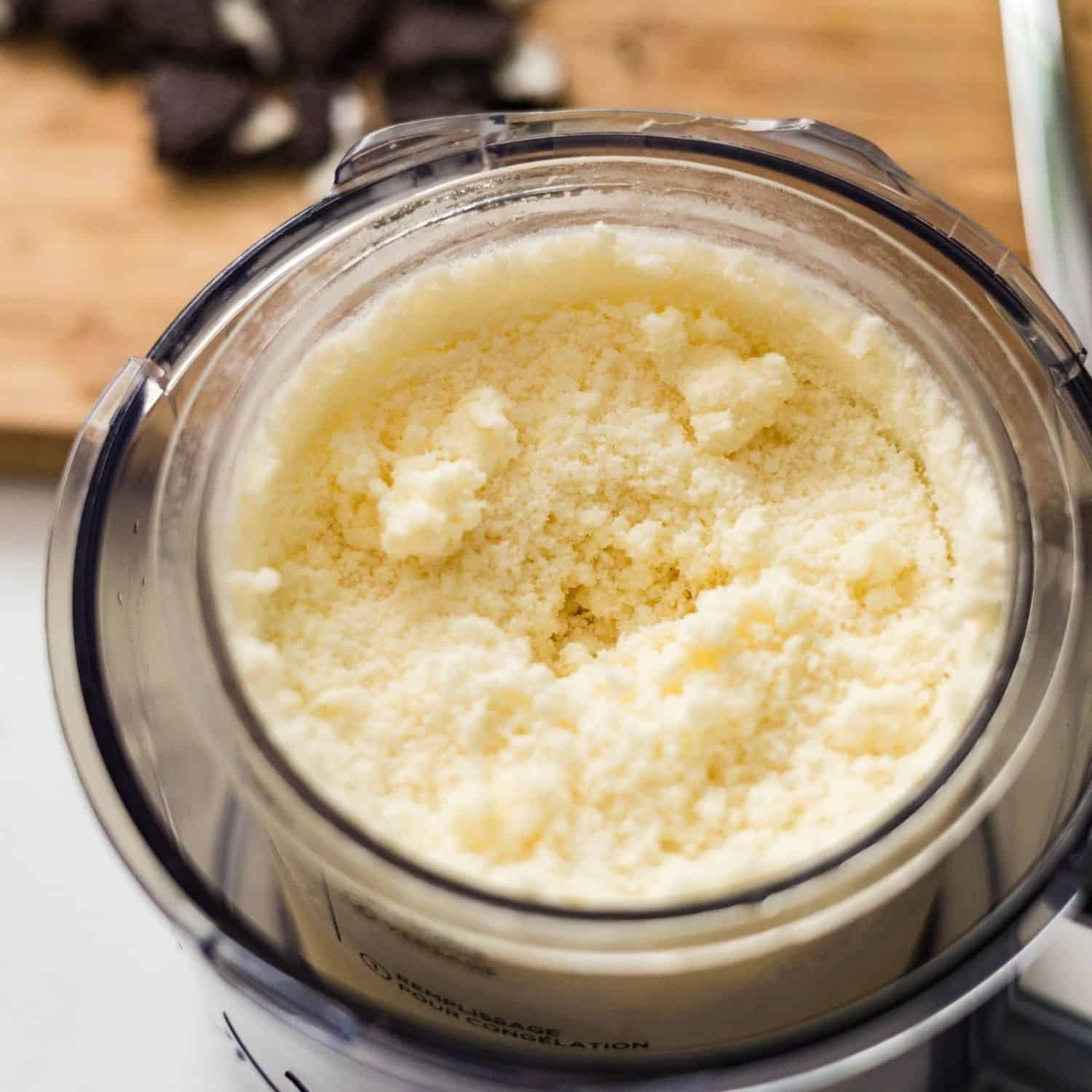 High protein cookies and cream ice cream in a Ninja Creami pint after one spin, still crumbly and needing another spin or mix-in step.