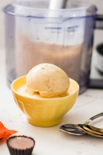 Scoops of Ninja Creami high protein peanut butter cup ice cream served in a yellow bowl with Reeseโs peanut butter cups nearby