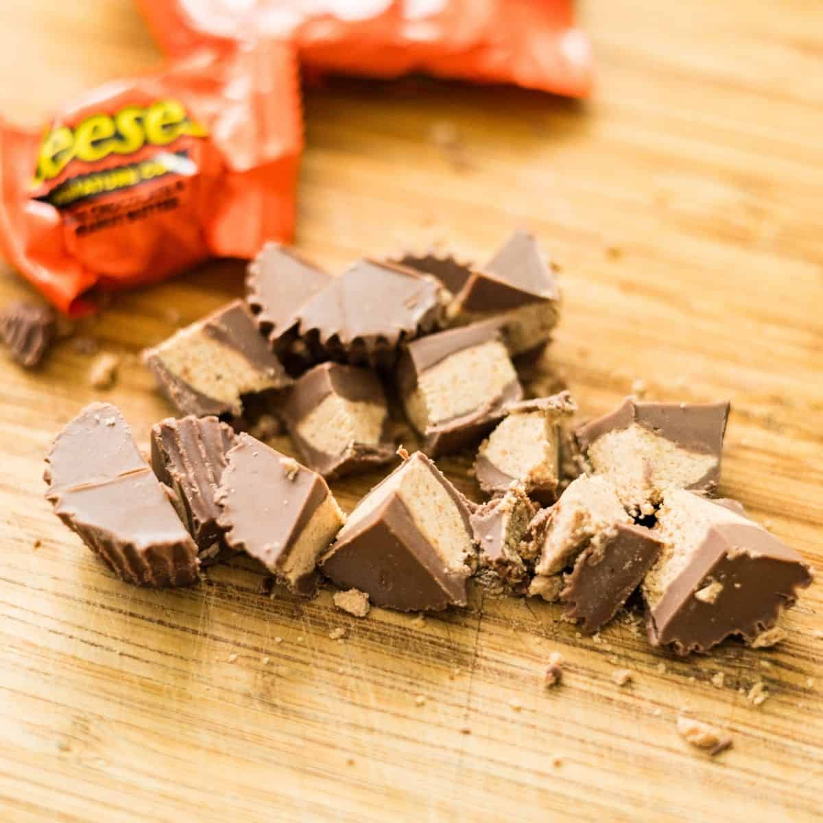 Chopped Reese’s peanut butter cups on a cutting board for peanut butter cup ice cream mix-ins