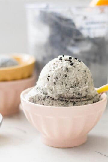 Homemade black sesame ice cream made in the Ninja Creami served in a bowl with the pint behind it