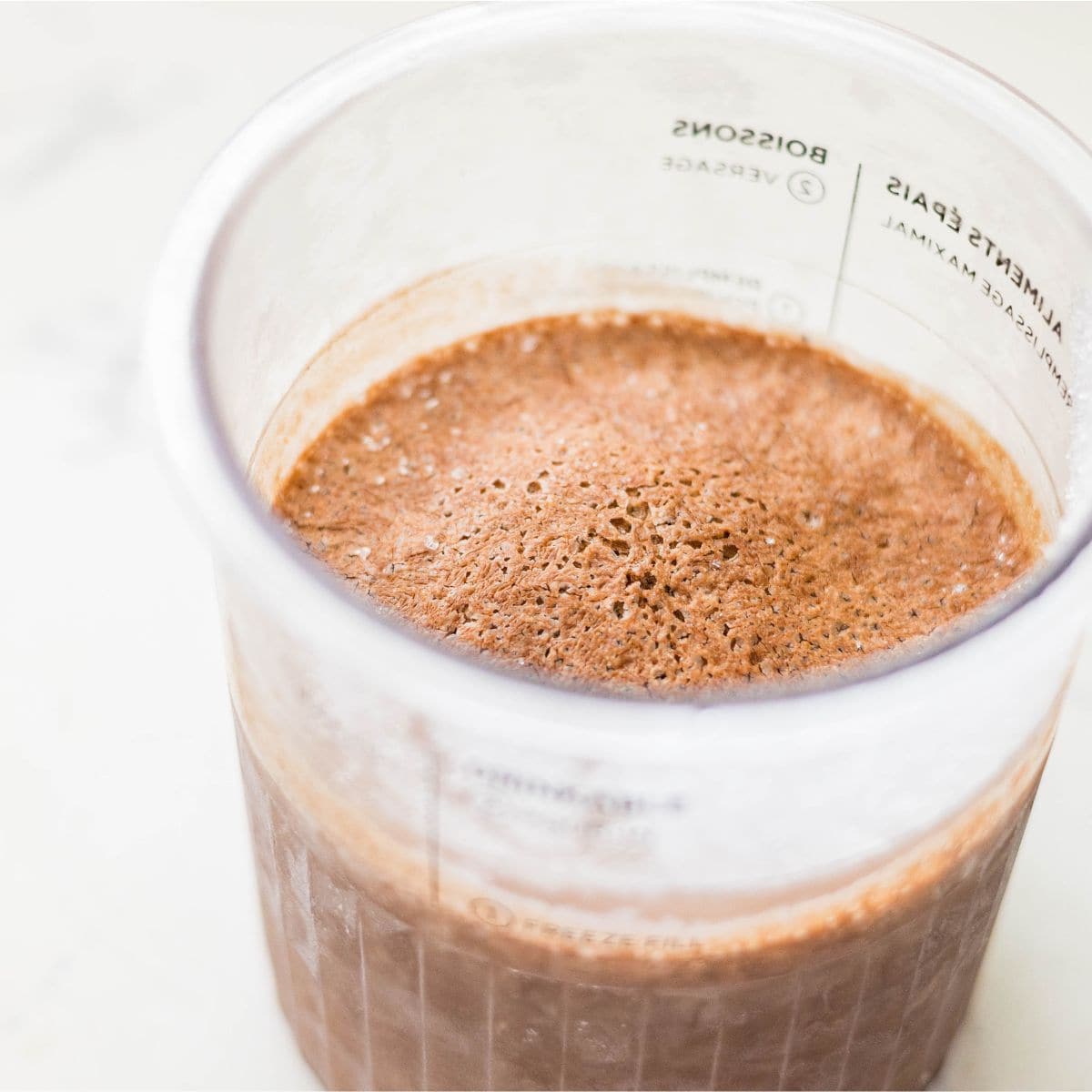 Frozen chocolate ice cream base in a Ninja Creami pint before spinning into rocky road ice cream