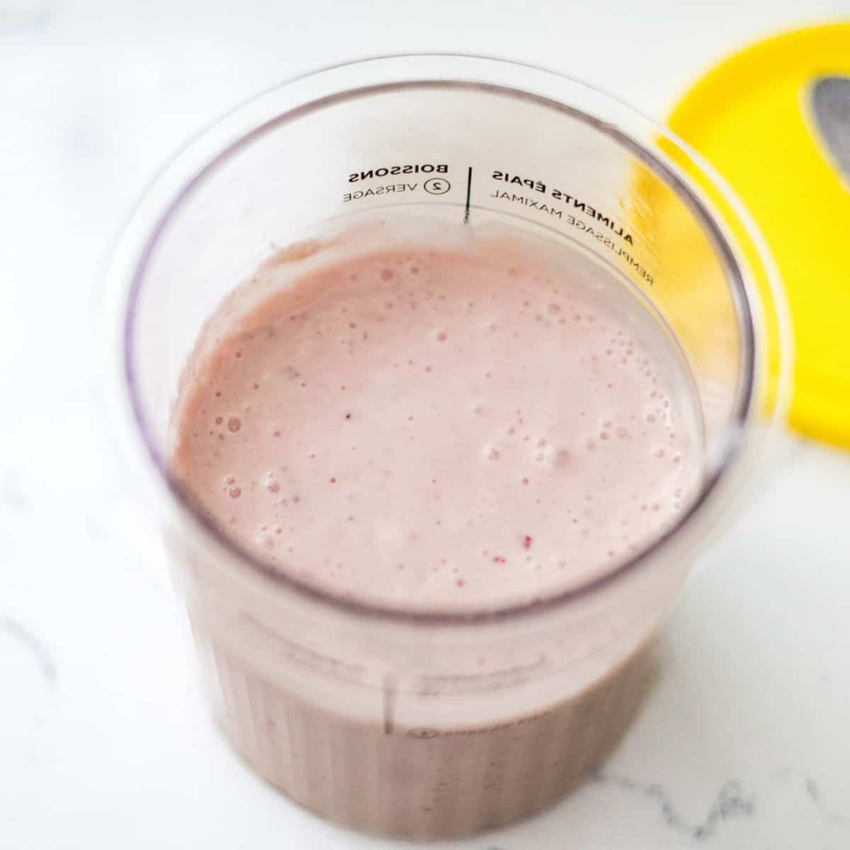Blended strawberry protein frozen yogurt mixture in a Ninja Creami pint before freezing