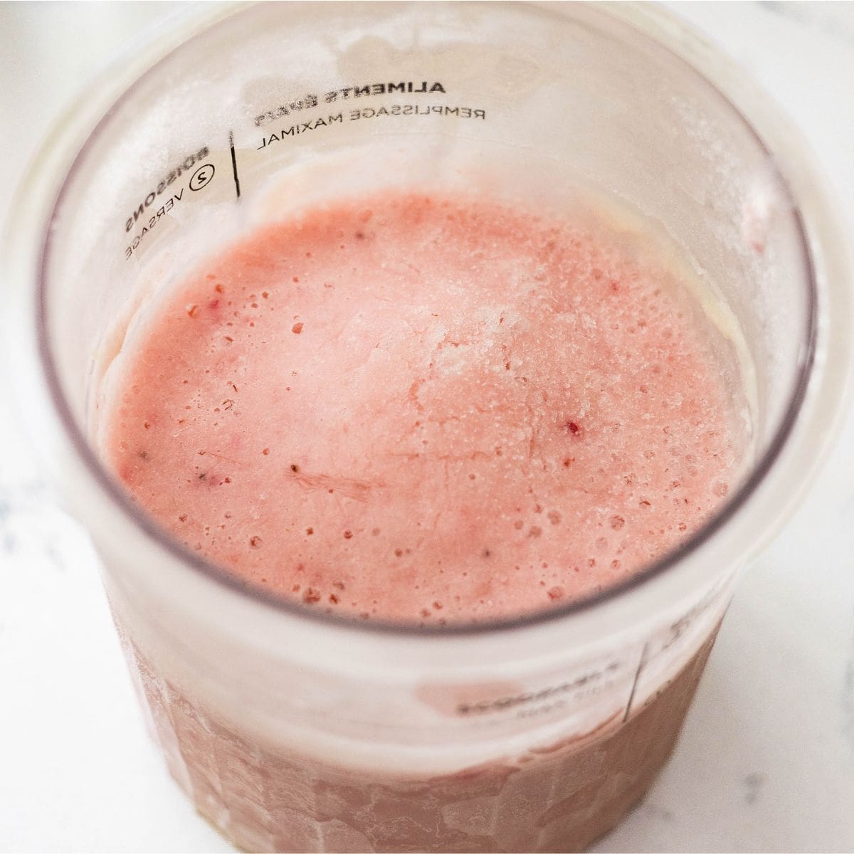 Frozen strawberry protein frozen yogurt base in a Ninja Creami pint before spinning