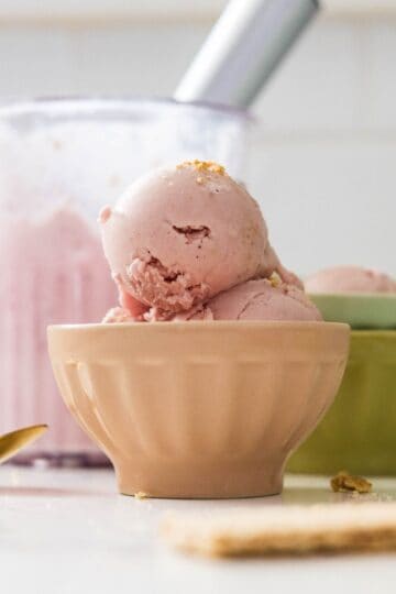 High protein strawberry cheesecake ice cream scoops served in a bowl with graham cracker crumbs