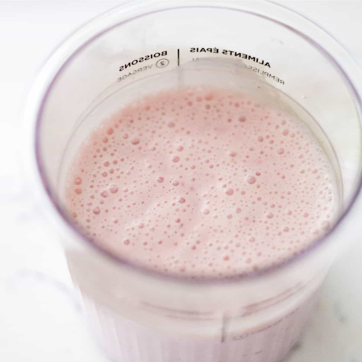 Blended strawberry cheesecake ice cream base in a Ninja Creami pint before freezing