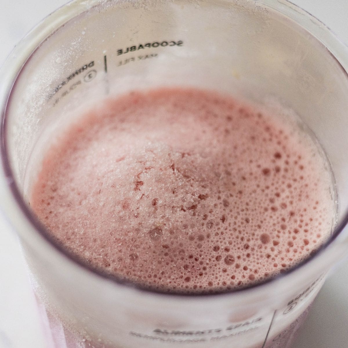 Frozen high protein strawberry cheesecake ice cream base in a Ninja Creami pint before spinning