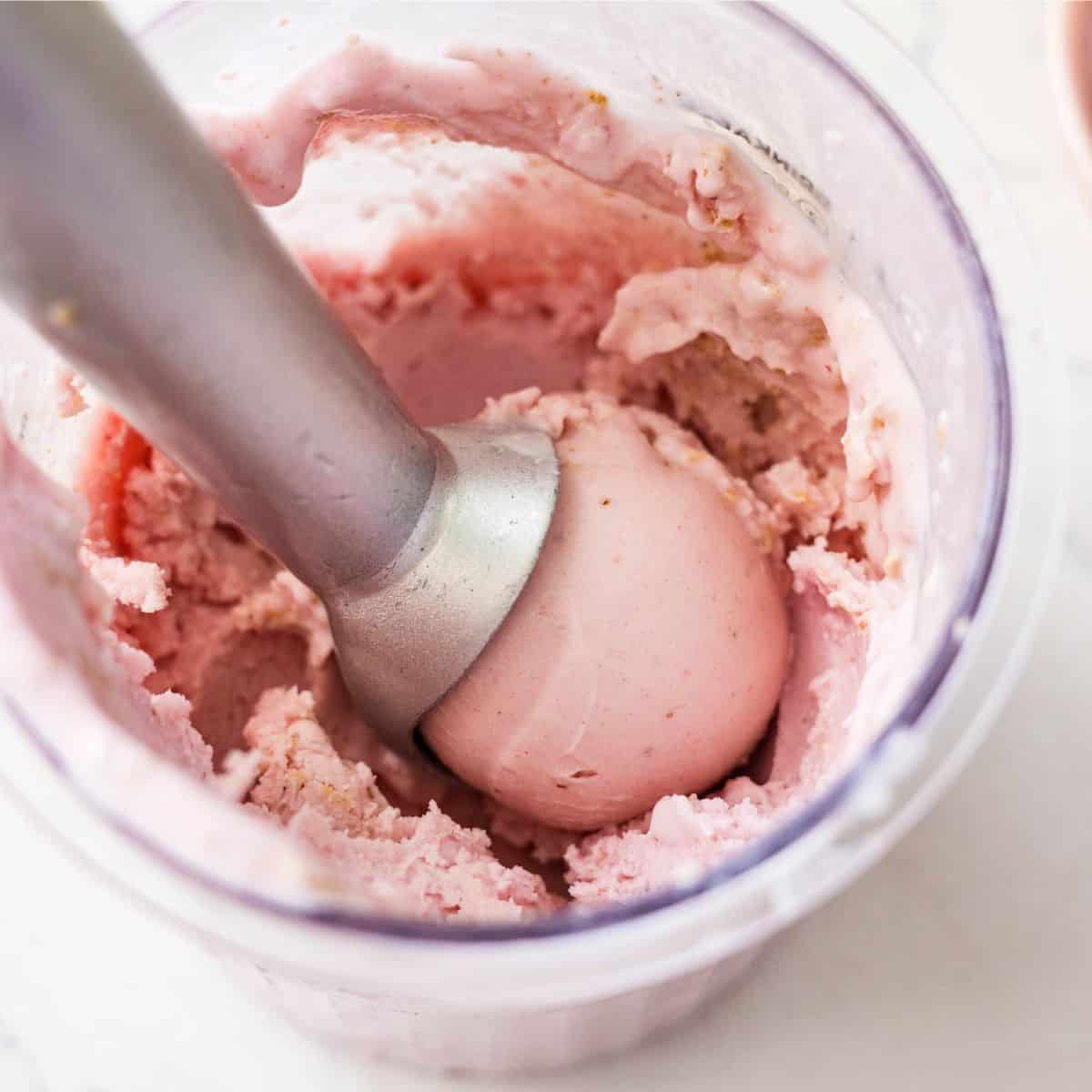 Scoop of creamy Ninja Creami strawberry cheesecake ice cream lifted from the pint container