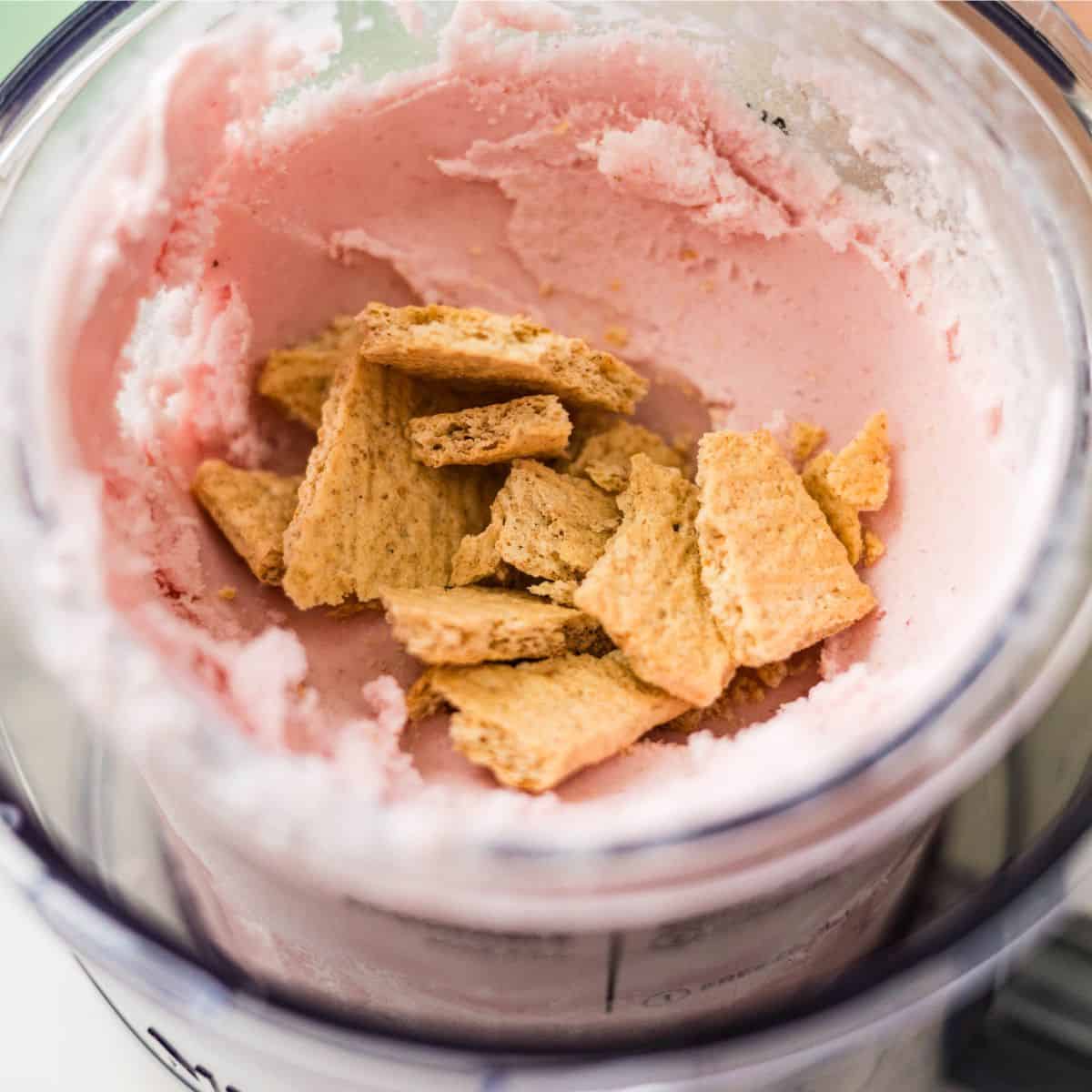 Graham cracker pieces added to Ninja Creami strawberry cheesecake ice cream before mixing