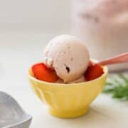 Ninja Creami strawberry banana ice cream served in a yellow bowl with sliced strawberries