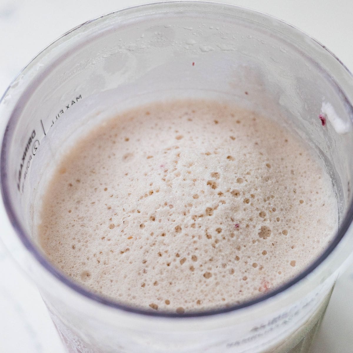 Frozen strawberry banana ice cream base in a Ninja Creami pint before spinning