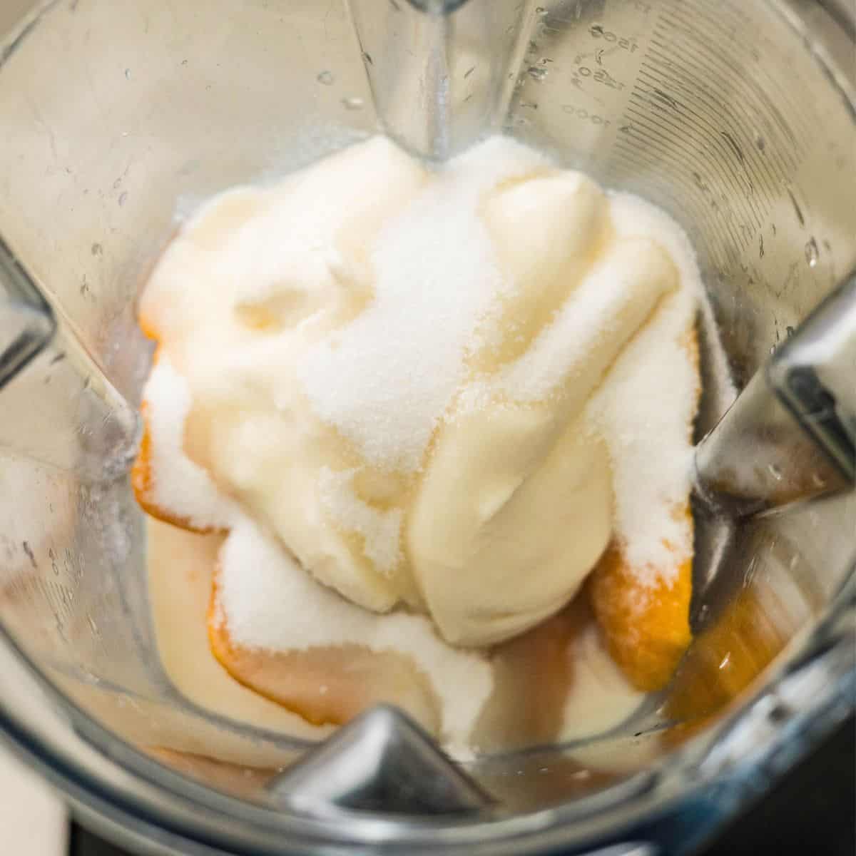 Frozen mangoes, Greek yogurt, and half and half in a blender for Ninja Creami mango frozen yogurt