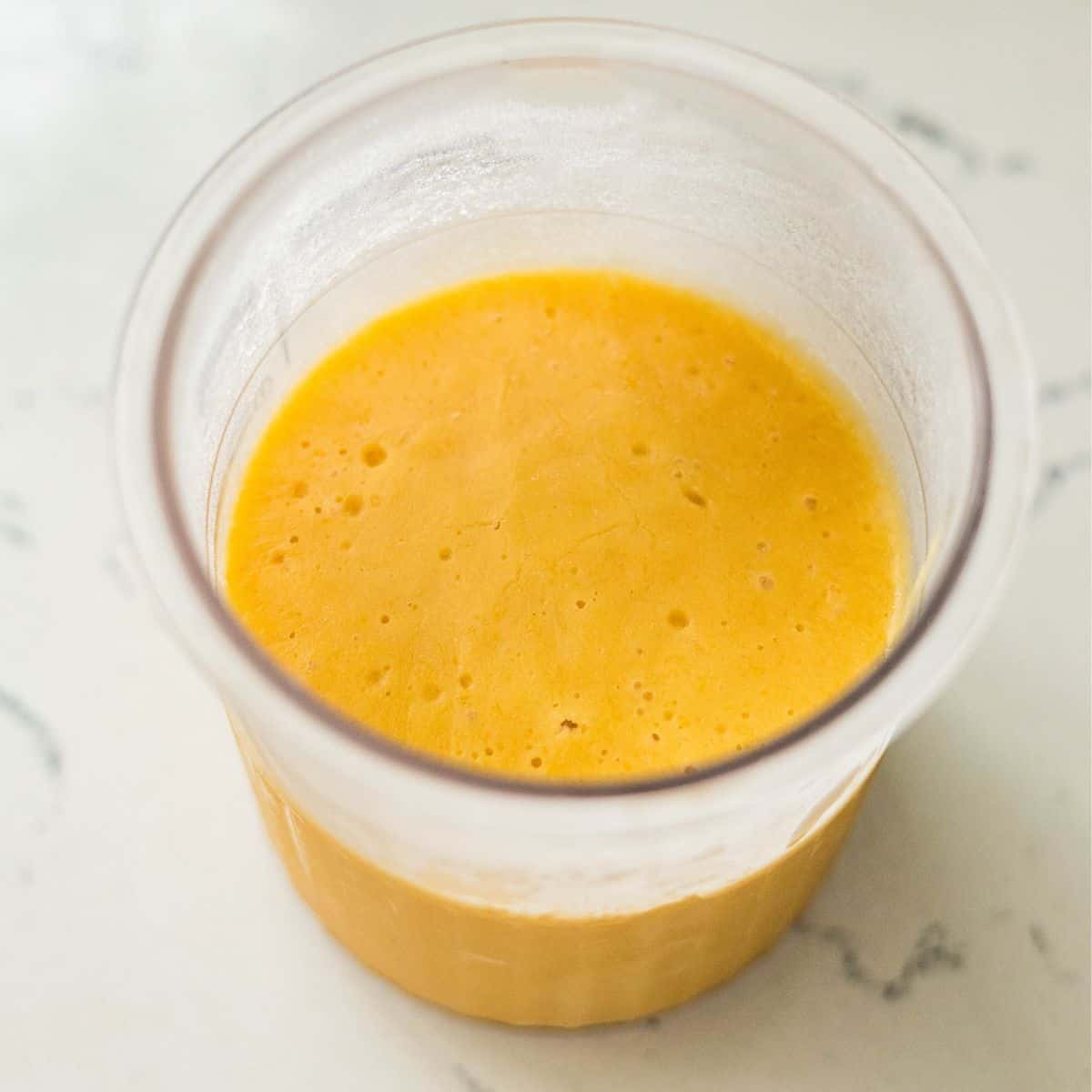 Frozen mango frozen yogurt base in a Ninja Creami pint, ready to spin