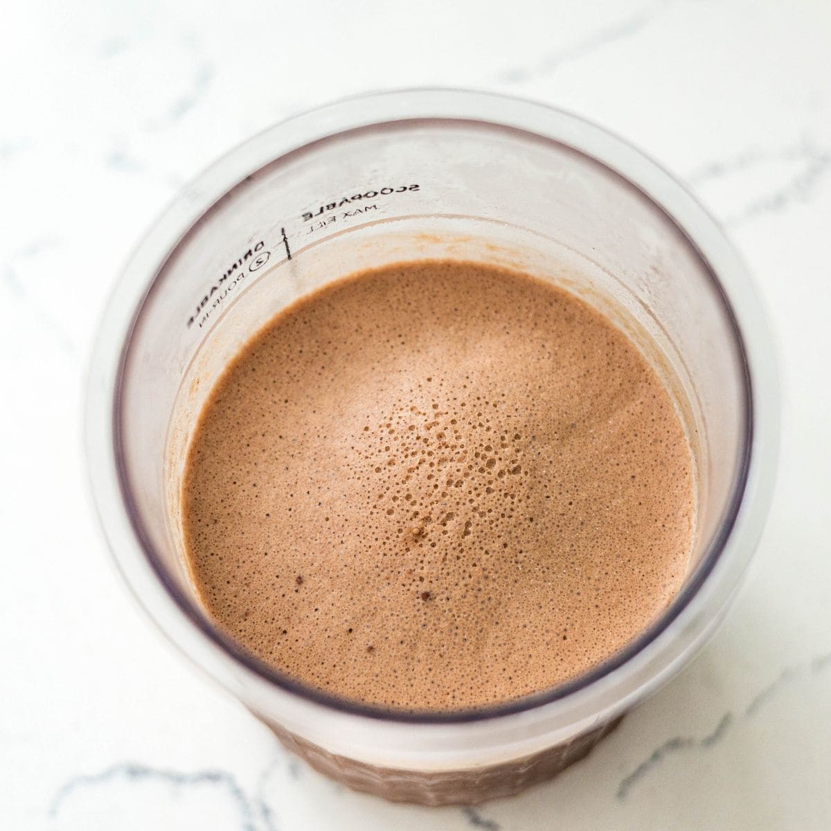 Frozen chocolate peanut butter ice cream base in a Ninja Creami pint, ready to spin