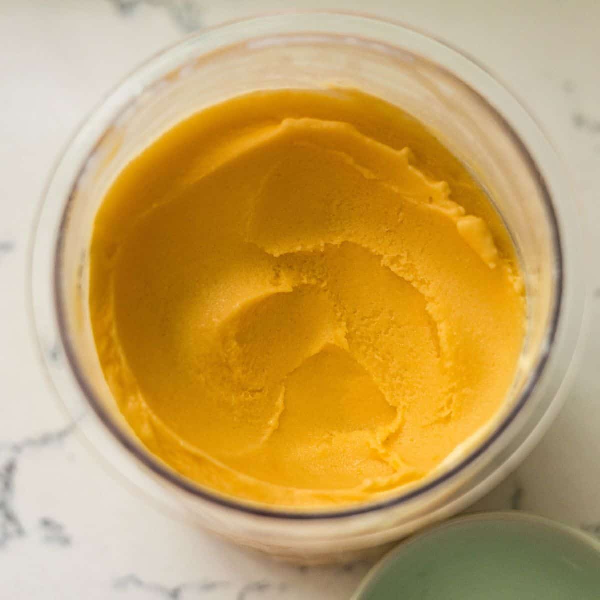 Smooth, creamy mango frozen yogurt in a Ninja Creami pint after a respin