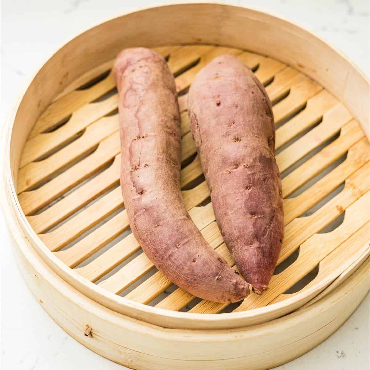 Two whole purple sweet potatoes in a bamboo steamer, ready to mash for Ninja Creami protein ice cream