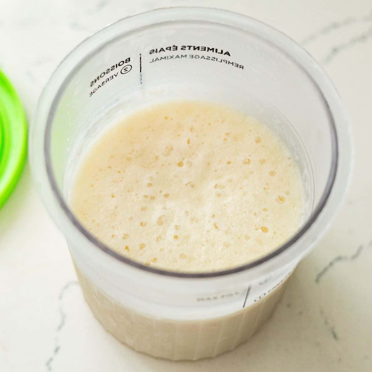 Blended vanilla protein ice cream base in a Ninja Creami container